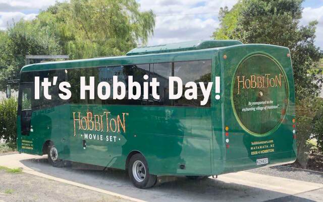 A green bus with text: "It's Hobbit Day! Hobbiton Movie Set."